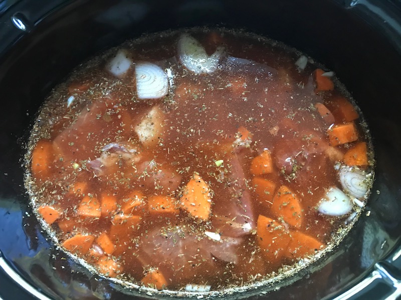 All ingredients in slow cooker insert for Paprika Pork Stew Recipe with carrots, onion, parsley.