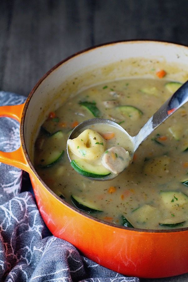 Creamy Chicken Sausage and Tortellini Soup in a large pot with ladle scooping.  It's silky and creamy with  onions, garlic, Chicken sausage, and zucchini bring so much flavor and texture.  The tortellini give that delicious salty, creamy, hearty bite! 