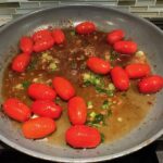 Bacon Tomato Sauce in pan for Smothered Chicken with Bacon, and Tomatoes. The chicken is smothered in a thickened sauce infused with smokey and salty bacon flavor.  Cherry tomatoes give a sweet and tangy pop.