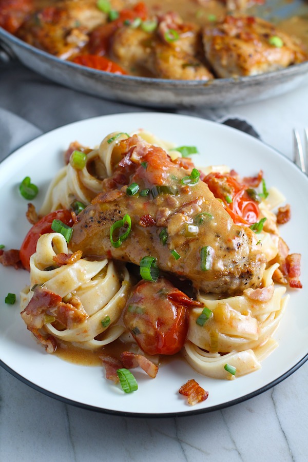 Photo of Smothered Chicken With Bacon And Tomatoes served on a white plate - by Talking Meals