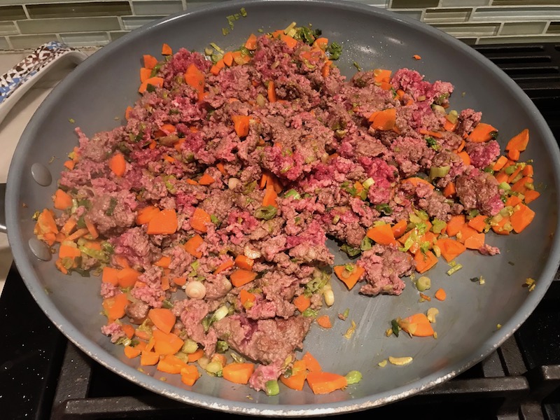 Carrots and raw beef mixture cooking in skillet for Empanada Beef Pie Recipe. It has a perfect flaky, buttery pastry on the outside with a savory, smokey, salty ground beef filling.  The best part is that everything cooks in one skillet!
