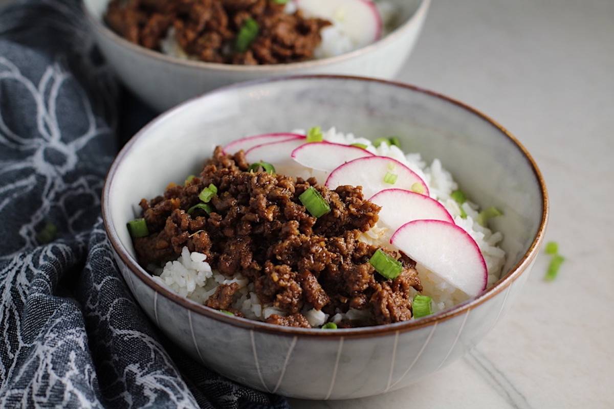 Korean Bulgogi Ground Beef and Rice Bowls with sliced radishes fanned out on top and scallion garnish.