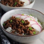 Korean Ground Beef and Rice Bowls with sliced radishes fanned out on top and scallion garnish.
