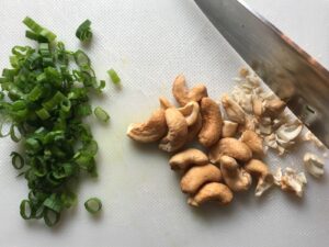 Cashews and scallions on cutting board with knife for Quick Cooking Creamy Chicken Paprika. It's creamy, smokey, rich, and hearty. This is an easy weeknight family dinner!