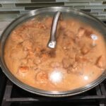 Chicken in sauce cooking in frying pan with glass cover for Quick Cooking Creamy Chicken Paprika. It's creamy, smokey, rich, and hearty. This is an easy weeknight family dinner!