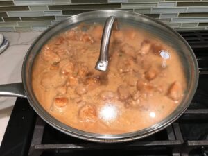 Chicken in sauce cooking in frying pan with glass cover for Quick Cooking Creamy Chicken Paprika. It's creamy, smokey, rich, and hearty. This is an easy weeknight family dinner!