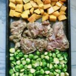 Sheet Pan Spanish Chicken thighs on a pan with Butternut Squash cubes in one side and Brussels Sprouts on the other! It's warm, hearty, and smoky.