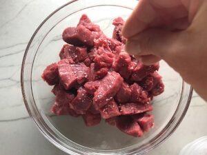 Hand seasoning raw steak bites for Garlic Potato and Steak Bites Recipe.  It's an easy and delicious, one-pan family dinner!  You get fantastic salty, buttery, tender steak and potatoes in each and every mouthwatering bite! 