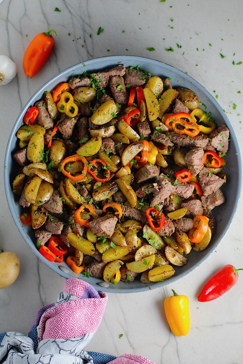 Garlic Potato and Steak Bites Recipe with sweet pepper slices in a pan on counter. It's an easy and delicious, one-pan family dinner!  You get fantastic salty, buttery, tender steak and potatoes in each and every mouthwatering bite! 