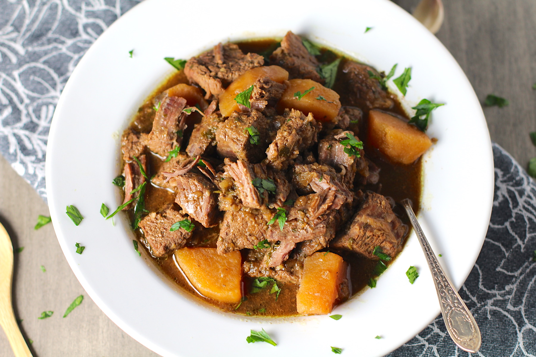 Slow Cooker Honey Garlic Beef and Potatoes in a bowl with parsley on top. It's a delicious easy dinner with tender beef cubes are cooked in the slow cooker with lots of delicious garlic, onions, and potatoes.  Then honey and molasses are added for that touch of sweet.