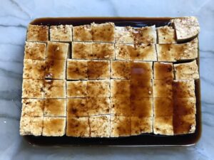 Firm tofu cut into cubes and marinating in teriyaki sauce for Thai Peanut Sauce Noodles with seared tofu and veggies.