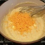 Whick mixing shredded cheddar into grits for Shrimp and Grits recipe.