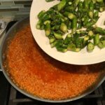 Adding cooked cut asparagus from a plate to risotto in pan for Asparagus and Tomato Quinoa Risotto