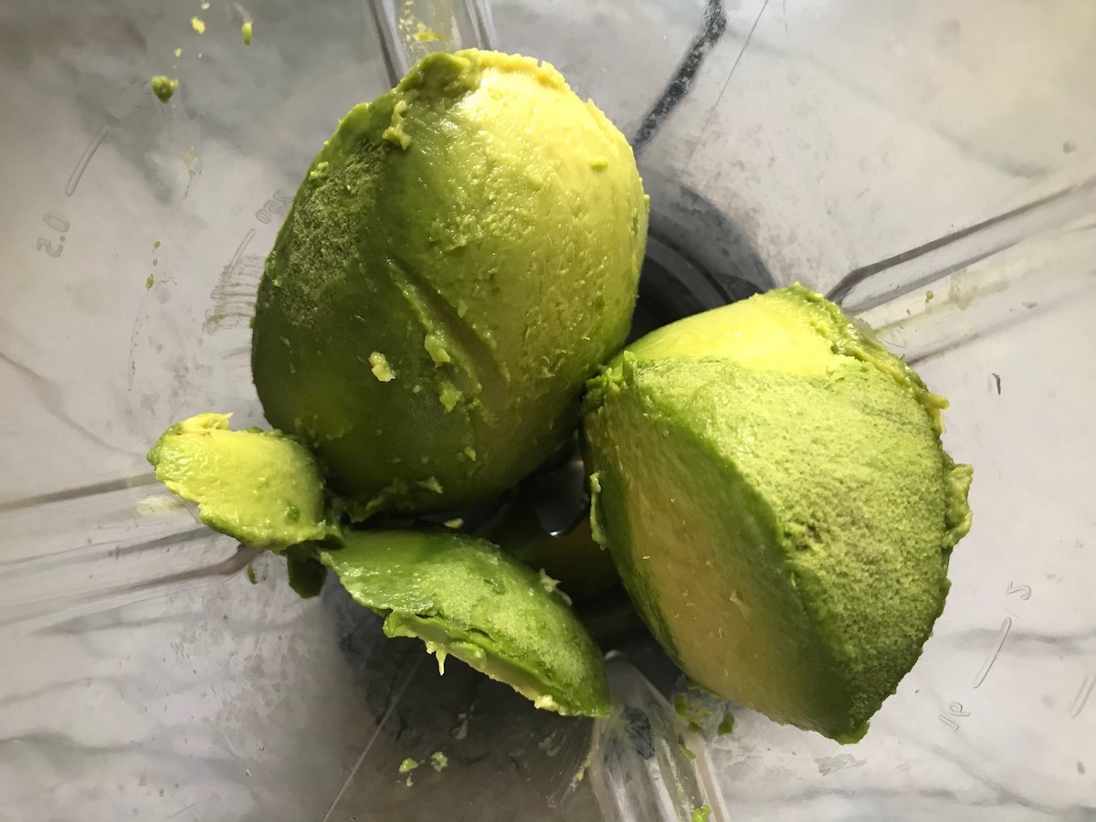 Whole Avocado pieces in a blender for Avocado Crema Recipe. It goes on everything! It's a creamy, tangy, rich and delicious sauce that's made in just minutes in the blender!