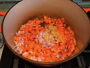 Diced carrots, onions, garlic, and ginger cooking in pot for Golden Carrot Ginger Soup Recipe. 