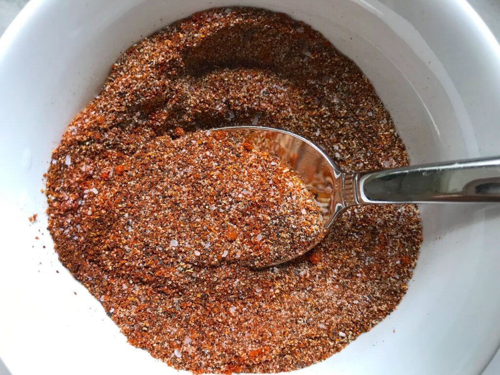 Cajun Seasoning in a bowl with spoon.  It's smokey, spicy, salty, peppery, and adds fast flare to so many different foods.