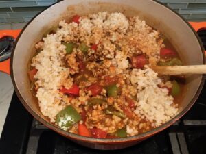 Mixing cooked rice into pot with ground chicken cooking, peppers, and tomatoes for Tex Mex Unstuffed Peppers with Ground Chicken.  Juicy Sweet Bell Peppers are chopped up and cooked with the Tex Mex style ground chicken, tomatoes, Mexican seasonings, cheese, rice and corn tortillas.