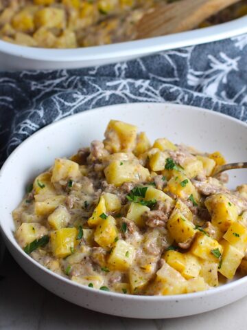 Cheesy Hamburger Potato Casserole in a bowl with a spoon. It's an easy, yummy, and cozy weeknight family dinner. 