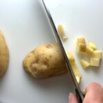 Knife dicing raw yukon gold potato with skin on for Cheesy Hamburger Potato Casserole. It's an easy, yummy, and cozy weeknight family dinner. 
