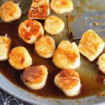 Glazed Pan Seared Scallops with Garlic and Honey in a pan with spatula