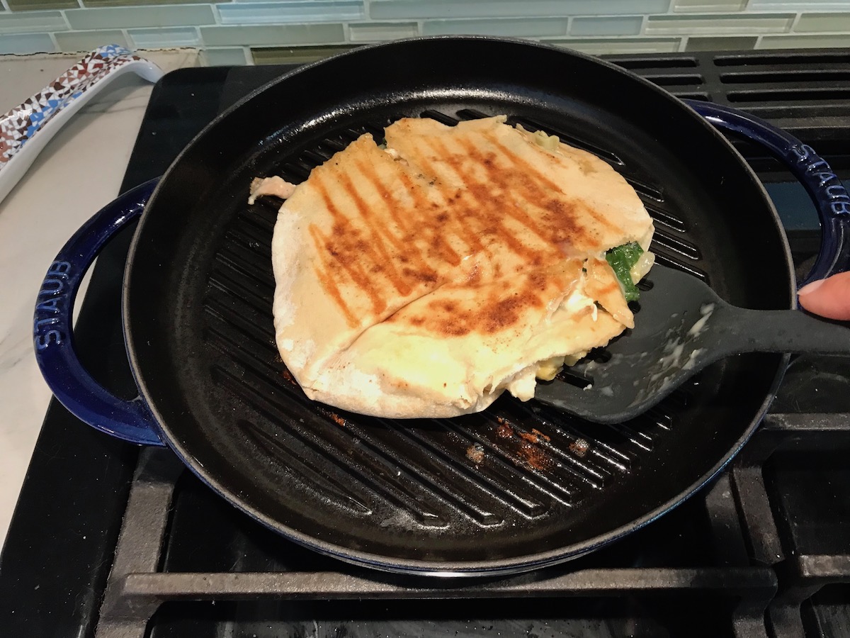 Spinach Artichoke Chicken Stuffed Pita grilling on a round grill pan on the stove.