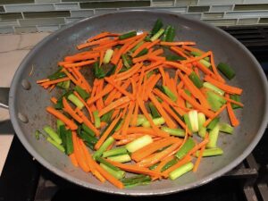 Carrot sticks and scallions cooking in a pan for this Cashew Chicken Lettuce Wrap Recipe