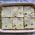 6 slices of swiss cheese added to the top of Chicken Wild Rice Casserole with Zucchini and Mushrooms in a casserole dish