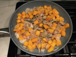 Butternut squash cubes and shallots cooking in a frying pan for Crispy Sage Chicken, Butternut Squash, and Shallots.