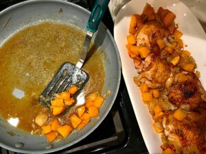 Spatula scooping butternut squash cubes and shallots from a frying pan next to platter with chicken for Crispy Sage Chicken, Butternut Squash, and Shallots.