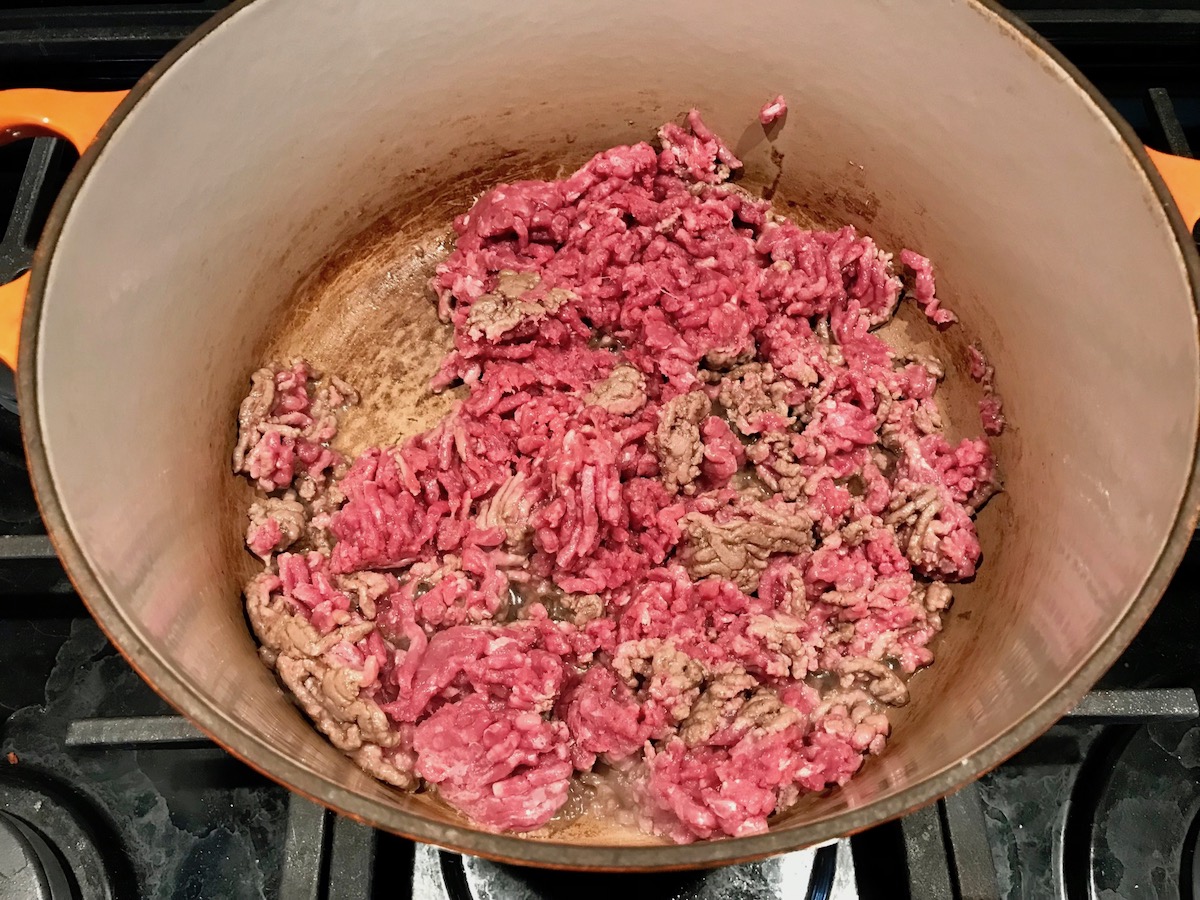 Raw ground beef cooking in a pot for Southwestern Pasta with Ground Beef and Corn and breadcrumbs. The sauce is thick and hearty with ground beef, sweet corn kernels, chunky tomatoes, chipotle peppers in adobo, green chiles, parmesan cheese, and lots of smokey and spicy seasonings.