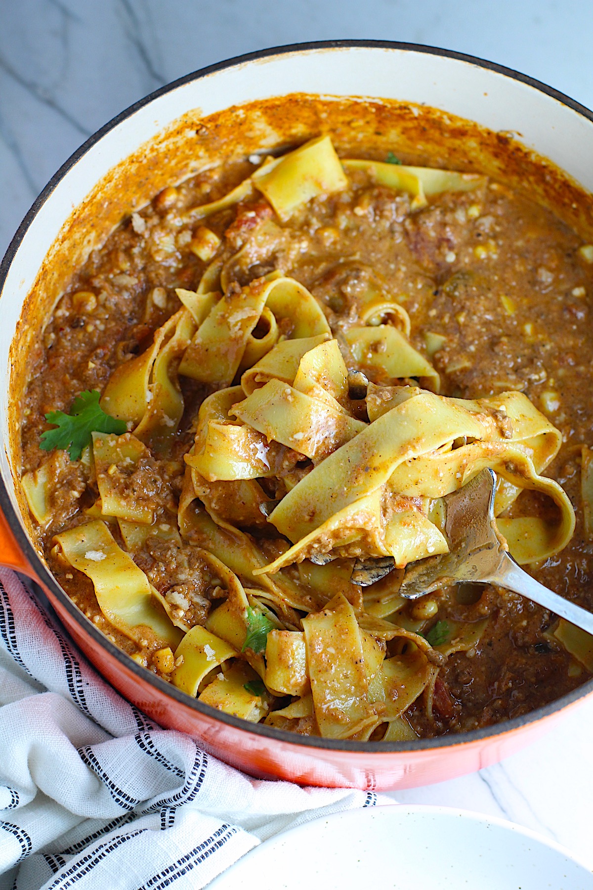 Southwestern Pasta with Ground Beef and Corn and breadcrumbs on top in pot with spoon scooping the pasta.