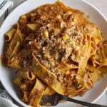 Southwestern Pasta with Ground Beef and Corn and breadcrumbs on top on a plate with fork holding a bite. The sauce is thick and hearty with ground beef, sweet corn kernels, chunky tomatoes, chipotle peppers in adobo, green chiles, parmesan cheese, and lots of smokey and spicy seasonings.