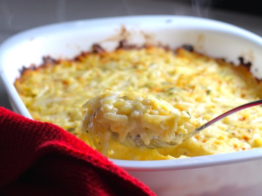 holiday side dishes - cheesy hash brown casserole with spoon scooping