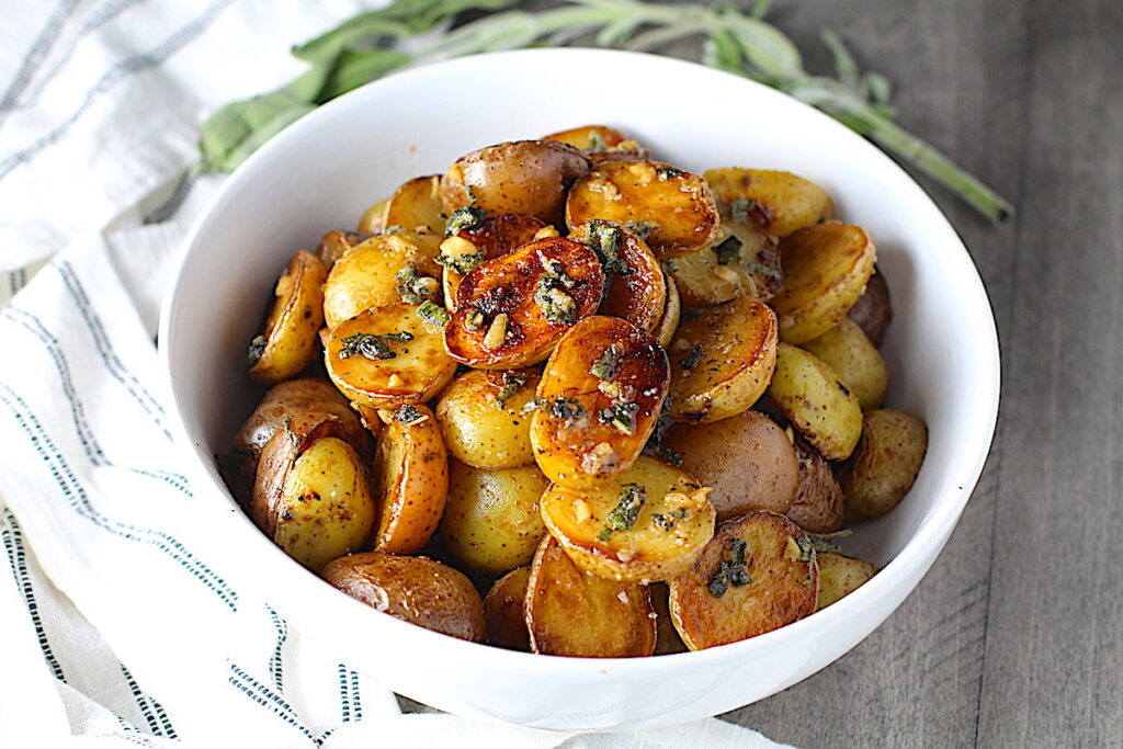 Crispy browned Sage Butter Potatoes in a bowl with garlic, sage butter glistening on top.