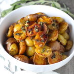Crispy browned Sage Butter Potatoes in a bowl with garlic, sage butter glistening on top.