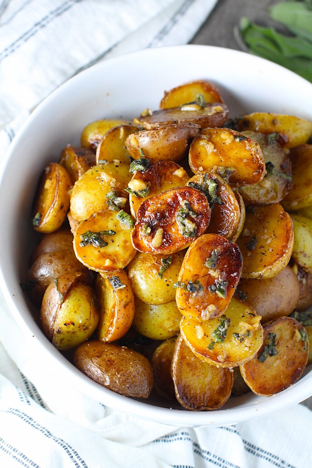 Crispy browned Baby Potatoes with Garlic Butter and Sage in a bowl with garlic, sage butter glistening on top.