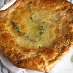 Puff Pastry Turkey Pot Pie in a casserole dish with fresh thyme on top and fresh sage on the counter. It's an easy dinner recipe to use leftover turkey from the holidays and ingredients you can have on hand!