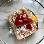 Raw ground chicken, diced onion, egg, and ketchup in a bowl for Ground Chicken Meatloaf. It's a perfect family dinner main dish!  10 minutes to prep and 45 minutes to bake.