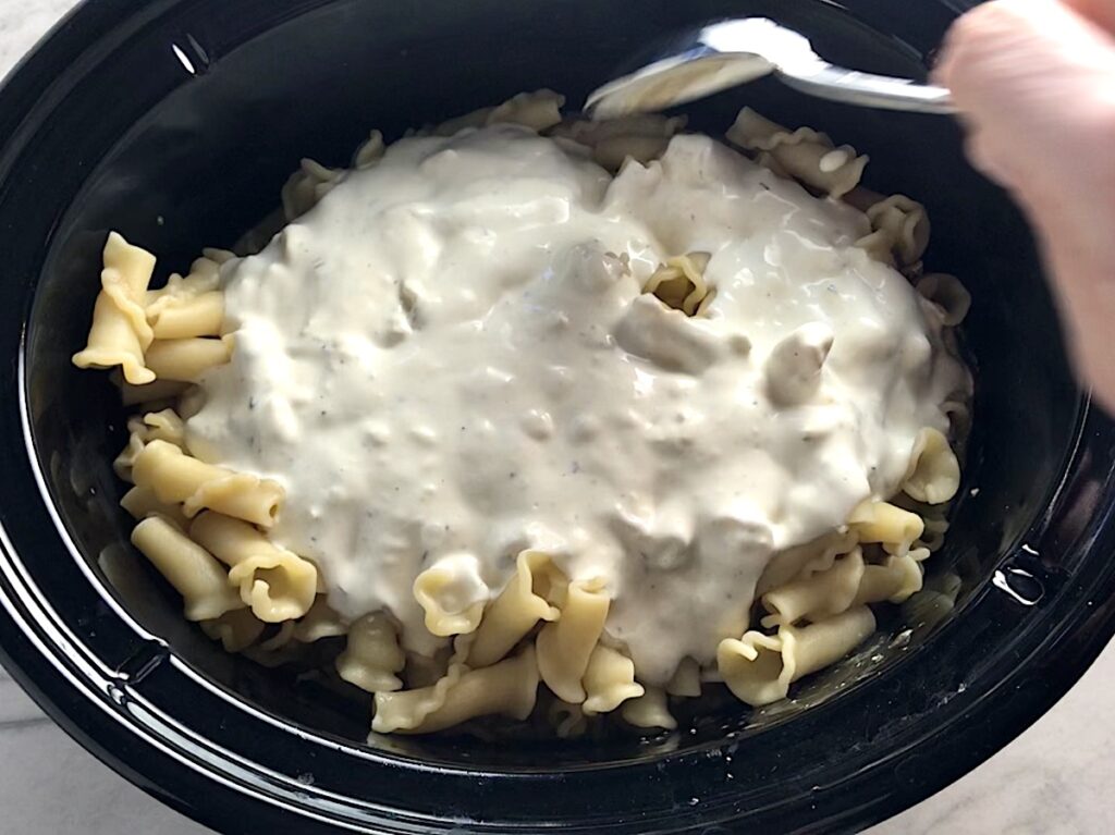 Creamy ingredients added to cooked pasta and chicken in crockpot for Ranch Chicken Crock Pot Pasta recipe. It uses fresh dill, parsley, and scallions is creamy, tangy, and utterly delicious!  It's also so easy to make, so it's a great weeknight dinner.