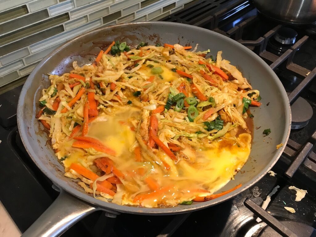 Shrimp Mei Fun Recipe, Singapore Noodles, in a pan with brown wood chop sticks on counter with napkin. It's an easy stir fry to make at home and tastes so much better than take out! With carrots, bean sprouts, curry powder, sesame oil, and more it's is a 30 minute weeknight dinner.