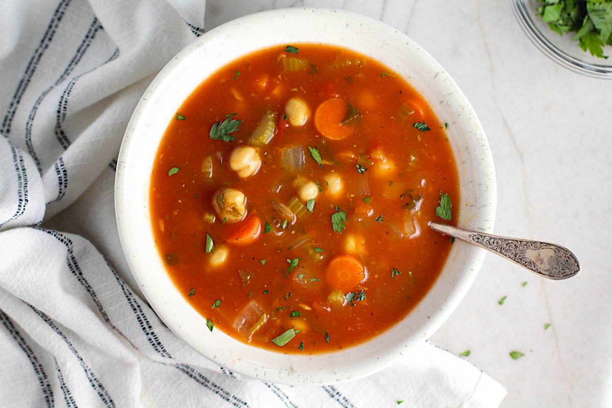 Vegetable Garbanzo Soup recipe in a bowl with a spoon on a counter with a napkin. It's slightly creamy and filled with flavor and texture! It's super easy to make ahead and enjoy during the week.
