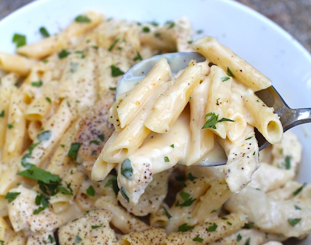 White Sauce Chicken Pasta Recipe on a plate with parsley garnish.