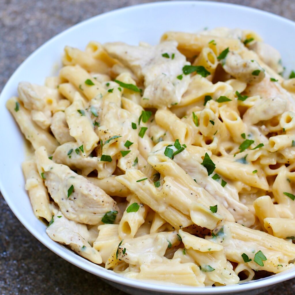 White Sauce Chicken Pasta Recipe on a plate with parsley garnish.