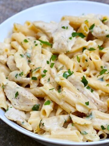 White Sauce Chicken Pasta Recipe on a plate with parsley garnish.