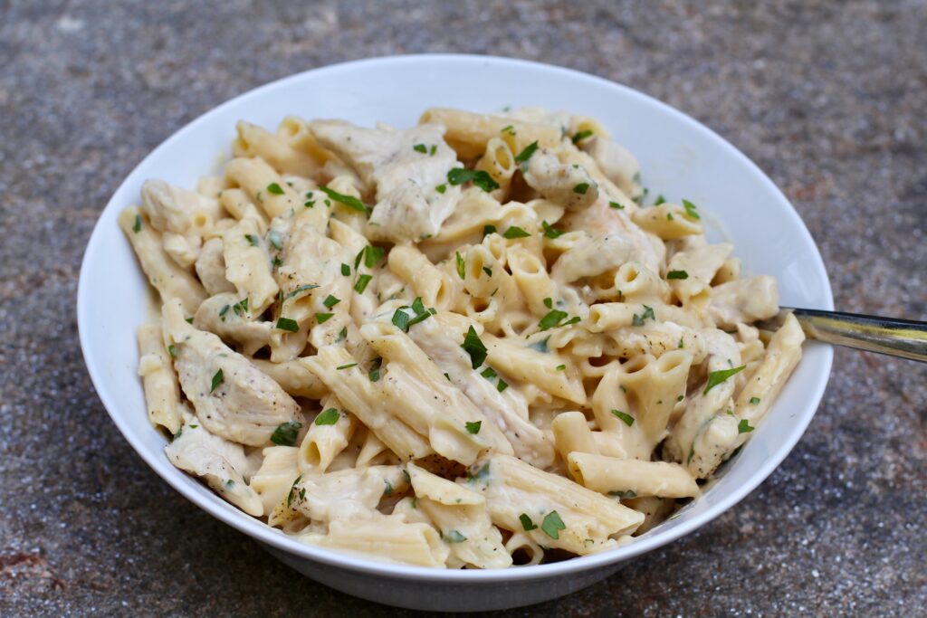 White Sauce Chicken Pasta Recipe on a plate with parsley garnish.