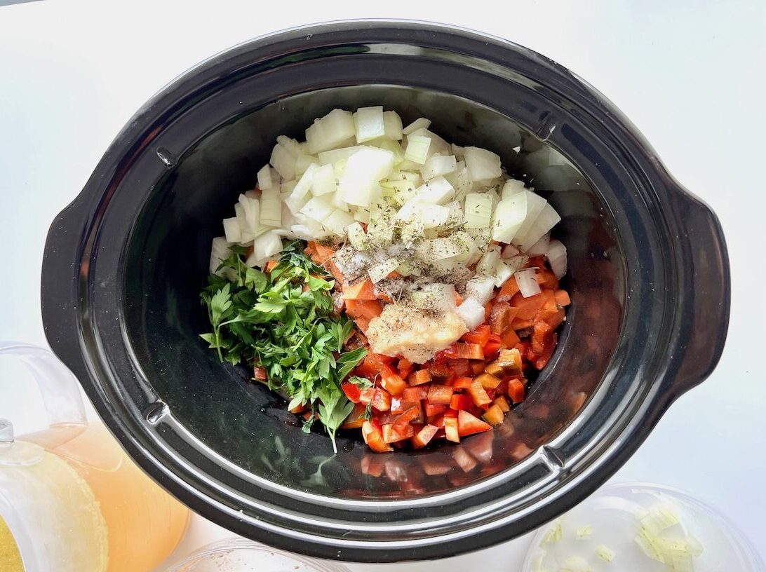 Diced carrots, celery, onions, garlic, and spices added to a slow cooker insert for Ground Beef Vegetable Soup Recipe. It's a perfect fall meal that's comforting, hearty, and delicious with loads of veggies!