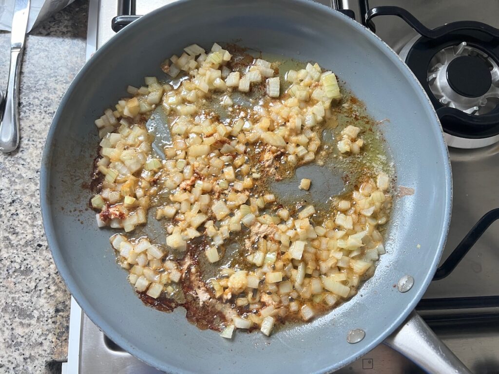 Onions cooking in butter in a pan for Pork Normandy recipe.