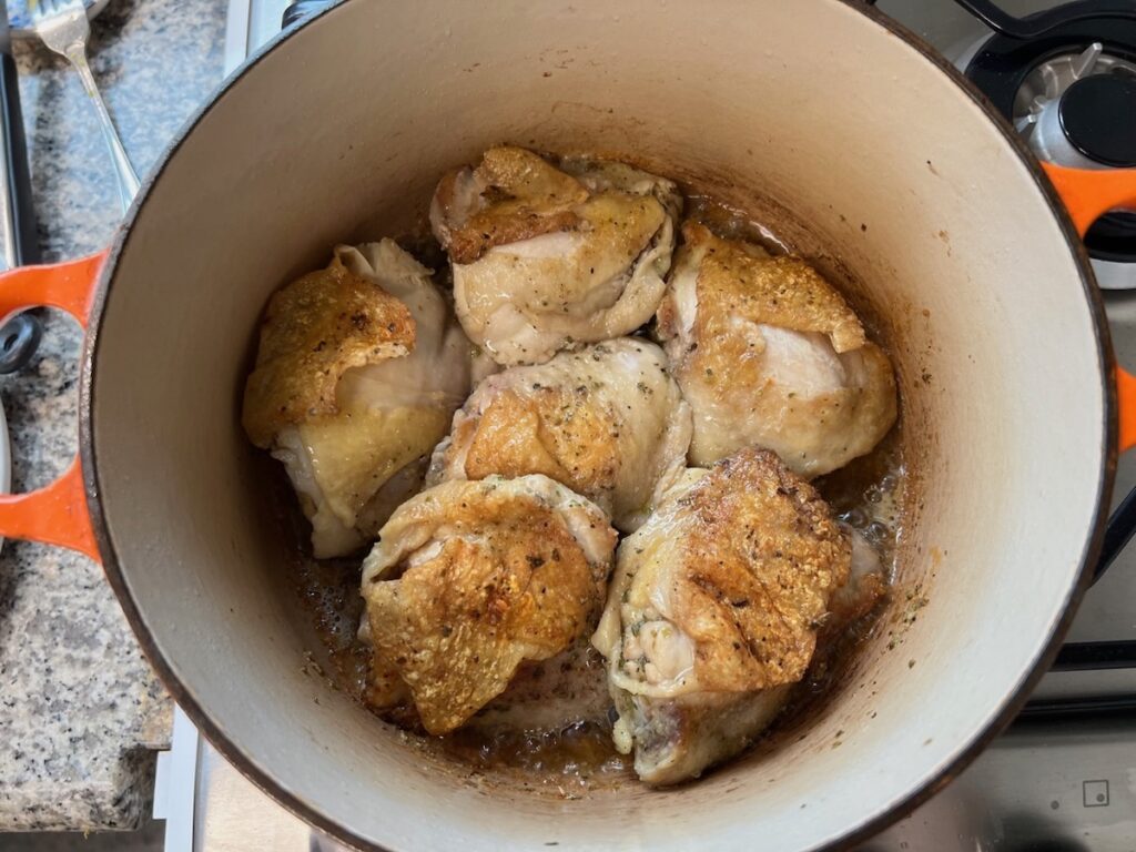 Chicken thighs cooking in a pot for Roasted chicken rice.