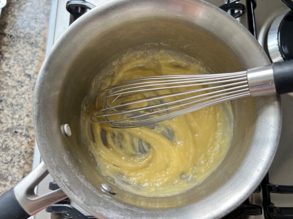 Melted butter and flour combined in a saucepan with whisk mixing them.