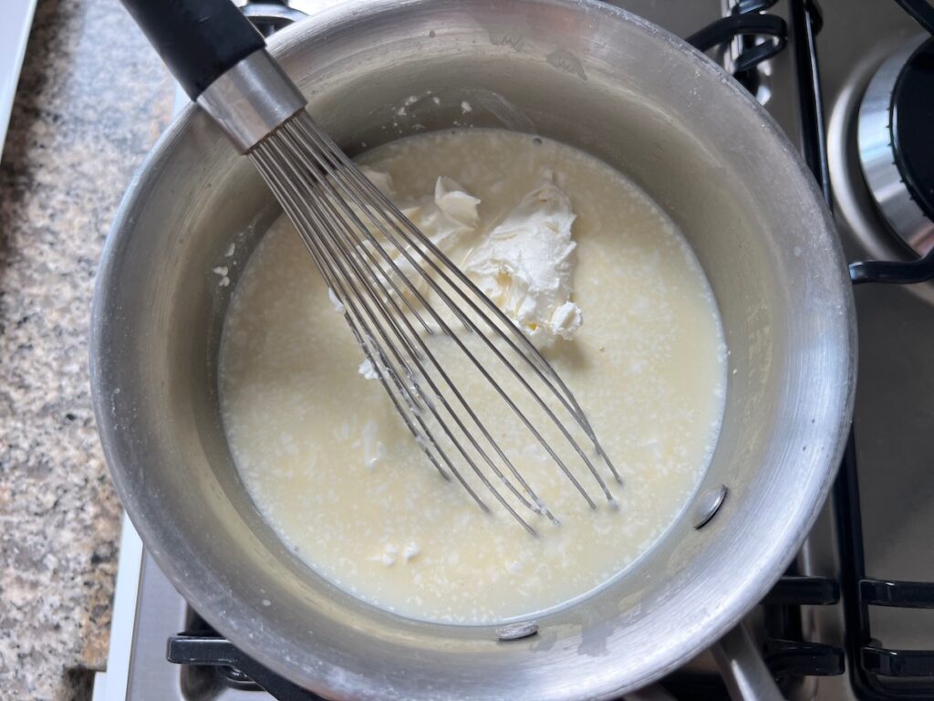 Cream cheese being mixed into the thickend sauce.